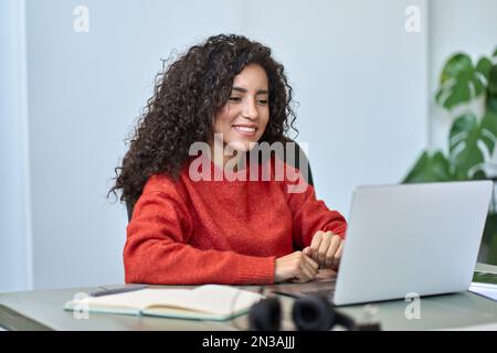 Giovane donna di affari latina felice che guarda il webinar online al lavoro sul notebook. Foto Stock