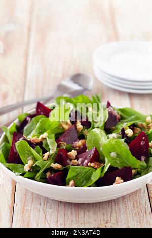 Insalata di barbabietole con verdure per bambini e noci in una ciotola con utensili da portata e piastre laterali Foto Stock