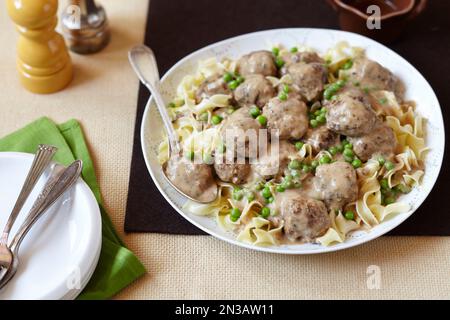 Polpette in salsa di panna su spaghetti con piselli Foto Stock