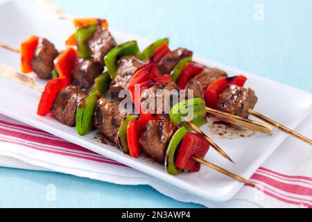 Bistecca alla griglia e spiedini di pepe su un piatto con tovagliolo a righe rosse Foto Stock