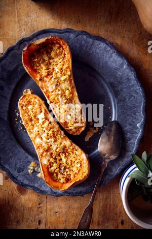 Zucca di zucca farcita al forno con formaggio e salvia su un piatto blu Foto Stock