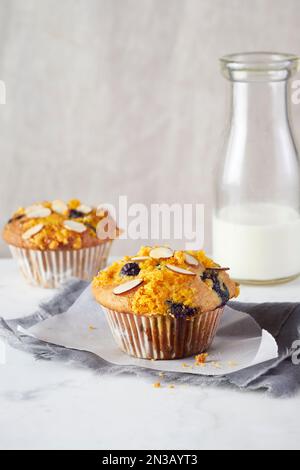 Muffin di mandorle e mirtilli e bottiglia di latte sullo sfondo Foto Stock