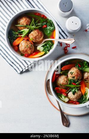 Ciotole di polpette di pollo asiatiche in brodo con verdure Foto Stock