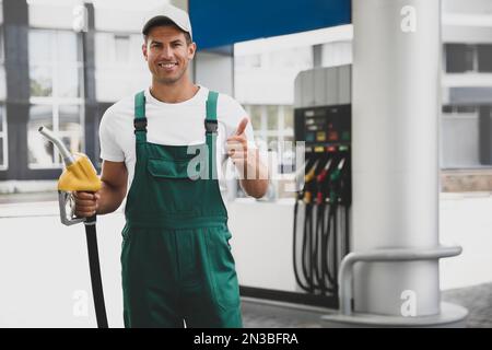 Operaio con ugello di pompa di combustibile a stazione di benzina moderna Foto Stock