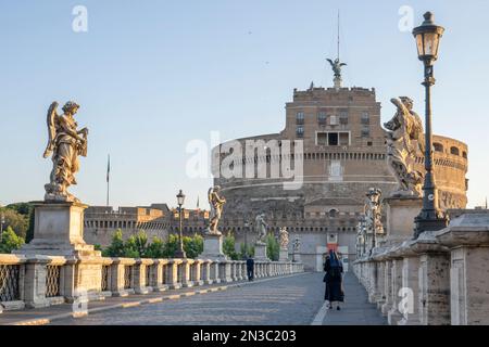 Veduta di Castel Sant'Angelo (Mausoleo di Adriano) con un pedone e una suora che attraversa il Ponte Sant'Angelo; Roma, Lazio, Italia Foto Stock
