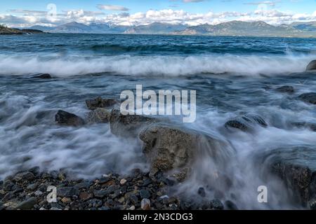 Le onde si infrangono sulla costa rocciosa del lago Kluane in una giornata ventosa. Il lago Klaune è il più grande lago dello Yukon; Yukon, Canada Foto Stock