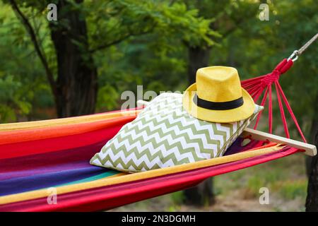 Amaca luminosa e confortevole con morbido cuscino e cappello al giardino verde, primo piano Foto Stock