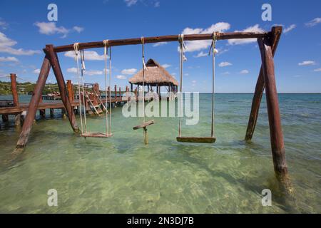 Altalena e gazebo Tiki Hut sul molo con acqua turchese al Rancho Encantado Eco-Resort & Spa di Bacalar; Quintana Roo, Messico Foto Stock