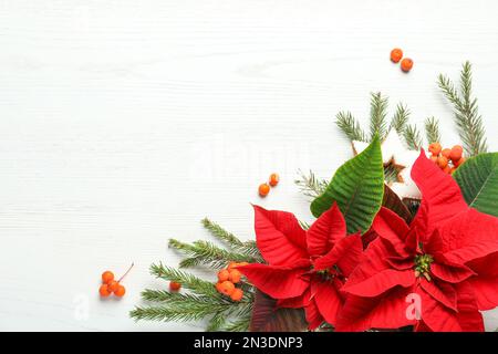 Composizione piatta con poinsettie (fiori di Natale tradizionali) e rami di abete su tavola di legno bianco. Spazio per il testo Foto Stock