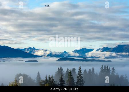 Una giornata nebbiosa rivela lentamente la baia di Kachemak, le montagne Kenai, le isole Cohen e Yukon e gli abeti rossi avvolti dalla nebbia da un ponte residenziale a Hom... Foto Stock