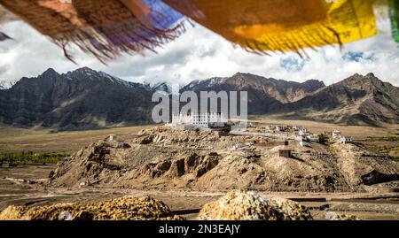 Panoramica del buddhista tibetano Stakna Gompa su uno sperone roccioso ai piedi dell'Himalaya, il quartiere di Leh, con colorate bandiere di preghiera... Foto Stock