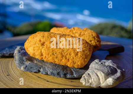 Coccodrillo pastais de bacalhau, spuntini tradizionali portoghesi serviti all'aperto con vista sull'oceano Atlantico blu vicino a Sintra nella zona di Lisbona, P Foto Stock