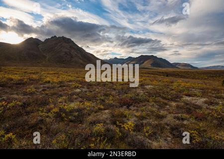 La luce del tramonto illumina le montagne e il paesaggio della Dempster Highway nel nord dello Yukon; Dawson City, Yukon, Canada Foto Stock