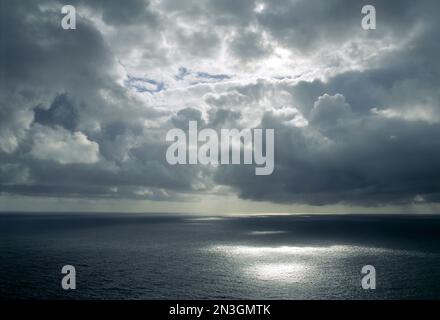 Splendide nuvole si librano su acque tranquille con riflessi solari e una tempesta in lontananza; Alaska, Stati Uniti d'America Foto Stock