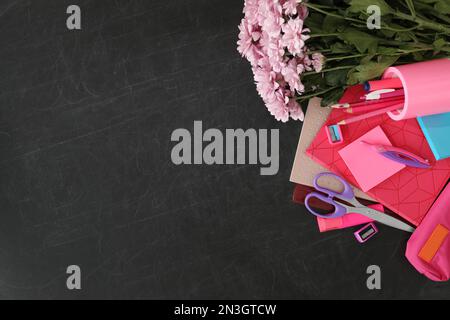 Cancelleria diversa scuola e bellissimi fiori rosa su lavagna, piatto con spazio per il testo. Buon giorno dell'insegnante Foto Stock