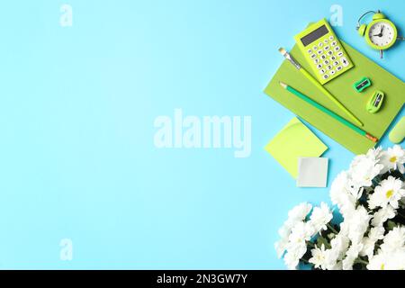 Cancelleria diversa scuola e bellissimi fiori bianchi su sfondo azzurro, piatto con spazio per il testo. Buon giorno dell'insegnante Foto Stock