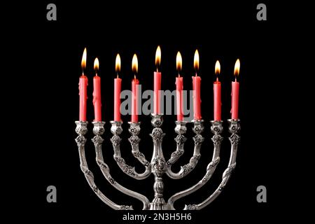 Menorah d'argento con candele accese su sfondo nero. Hanukkah celebrazione Foto Stock