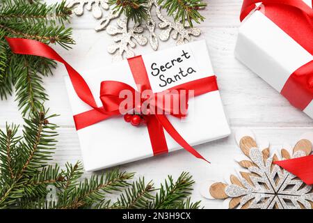 Composizione piatta con regali da Santa segreta su tavola di legno bianco Foto Stock