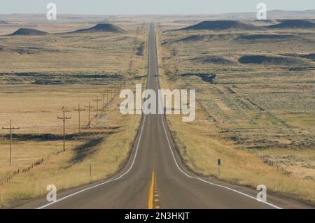 Strada di campagna vuota a due corsie che si dirige direttamente in lontananza nella campagna del Montana; Billings, Montana, Stati Uniti d'America Foto Stock