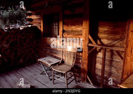 Legna da ardere e sedia sul portico di una capanna da caccia; Montana, Stati Uniti d'America Foto Stock