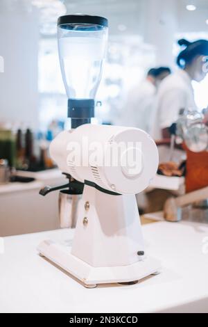 Chicchi di caffè appena macinati con questa macinacaffè a profondità di campo poco profonda in un bar. Bokeh aggiunge un tocco da sogno a questo ritratto o ve Foto Stock