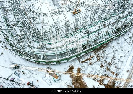 vista aerea dall'alto del cantiere innevato con gru gialla. nuovo stadio in costruzione. Foto Stock