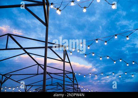 Serie di decorazioni a lampadina e tende per attività all'aperto, feste, concerti, festival, fiera del divertimento. Luci per la strada all'esterno Foto Stock