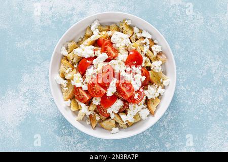 Dakos o insalata di koukouvagia. Ricetta classica insalata di fette biscottate di orzo cretese con pomodoro fresco, mizithra e origano. Tradizionale greco mediterraneo cu Foto Stock