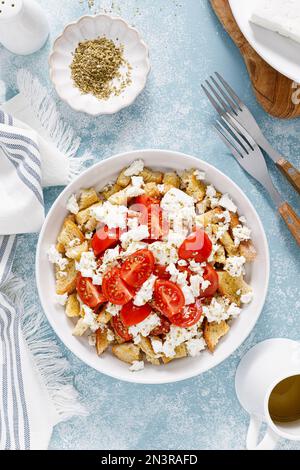 Dakos o insalata di koukouvagia. Ricetta classica insalata di fette biscottate di orzo cretese con pomodoro fresco, mizithra e origano. Tradizionale greco mediterraneo cu Foto Stock