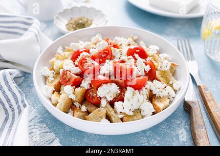 Dakos o insalata di koukouvagia. Ricetta classica insalata di fette biscottate di orzo cretese con pomodoro fresco, mizithra e origano. Tradizionale greco mediterraneo cu Foto Stock