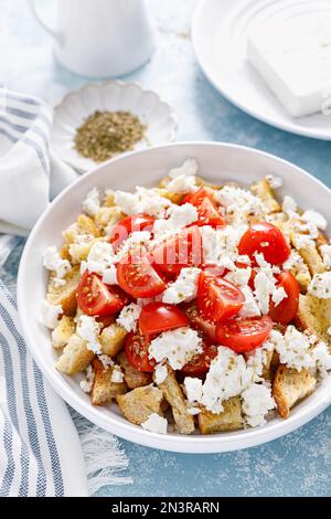 Dakos o insalata di koukouvagia. Ricetta classica insalata di fette biscottate di orzo cretese con pomodoro fresco, mizithra e origano. Tradizionale greco mediterraneo cu Foto Stock