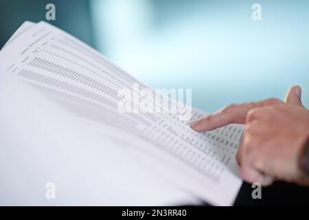 Scorrendo attraverso le figure. Immagine ritagliata delle mani di un imprenditore che indica documenti finanziari. Foto Stock