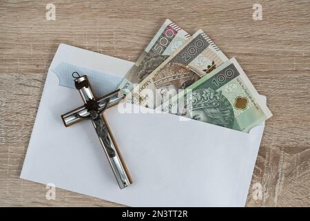 Visita Pastorale o Kolęda, tradizione cattolica dopo Natale in Polonia. Croce e busta con denaro polacco per sacerdote. Koleda donazione per la chiesa. Foto Stock