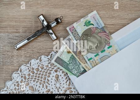Visita Pastorale o Kolęda, tradizione cattolica dopo Natale in Polonia. Croce e busta con denaro polacco per sacerdote. Koleda donazione per la chiesa. Foto Stock
