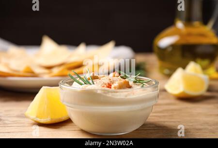 Delizioso hummus fatto in casa in una ciotola di vetro su un tavolo di legno Foto Stock