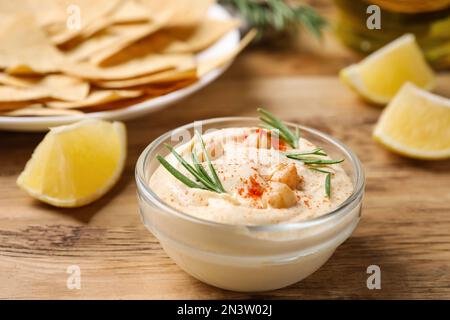 Delizioso hummus fatto in casa in una ciotola di vetro su un tavolo di legno Foto Stock