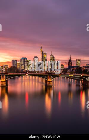 Vista dal Floeserbruecke sul fiume meno, sul ponte Ignatz-Bubis-Bruecke fino allo skyline e ai grattacieli. Bellissimo tramonto a Francoforte Foto Stock