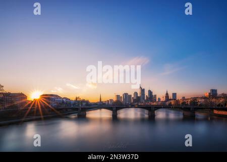 Vista dal Floeserbruecke sul fiume meno, sul ponte Ignatz-Bubis-Bruecke fino allo skyline e ai grattacieli. Bellissimo tramonto a Francoforte Foto Stock