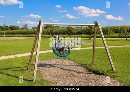 Donna in altalena nel giardino di Eden, parco di generazione attiva, parco sensoriale e di terapia, Untermarchtal, Baden-Wuerttemberg, Germania Foto Stock