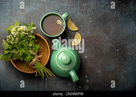 Tè alle erbe con erbe e fiori medici freschi, tisana, tisana e bouquet di fiori freschi e erbe curative vista dall'alto su sfondo di pietra Foto Stock