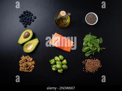 Set di prodotti alimentari come fonti di grassi sani, ingredienti ricchi di acidi grassi Omega: Filetto di salmone, verdure, bacche, noci, semi, olio d'oliva attivato Foto Stock