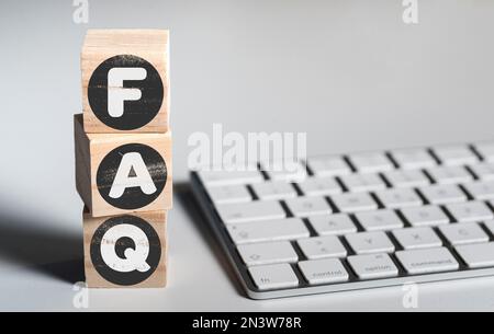 FAQ sui blocchi di legno sulla scrivania da ufficio con tastiera del computer, domande frequenti concetto Foto Stock