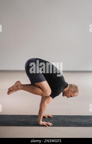 Un uomo di costruzione atletica fa yoga in palestra su un tappetino. Foto Stock
