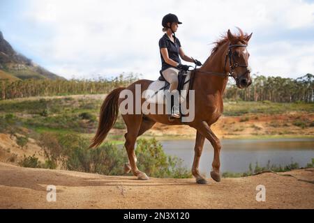 Libera come il vento... Una bella giovane donna che cavalca su un cavallo di castagno. Foto Stock