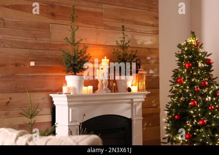 Bella sala interna con abeti in vaso, camino e decorato albero di Natale Foto Stock