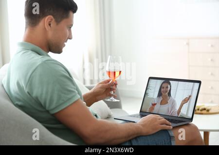 Amici che bevono vino mentre comunicano attraverso la videoconferenza online a casa. Distensione sociale durante la pandemia di coronavirus Foto Stock