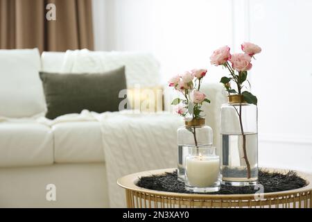 Candela bruciante e vasi con belle rose sul tavolo al coperto, spazio per il testo. Elementi interni Foto Stock