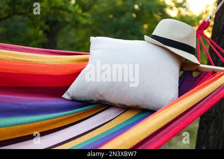 Amaca luminosa e confortevole con morbido cuscino e cappello al giardino verde, primo piano Foto Stock