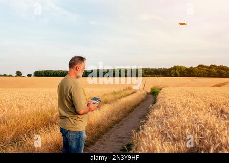 Uomo bearded che utilizza un drone con telecomando per realizzare foto e video, divertendosi con le nuove tendenze tecnologiche Foto Stock