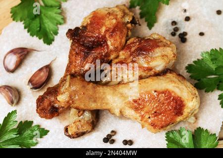 Cosce di pollo arrosto con spezie ed erbe su sfondo chiaro . Prezzemolo, aglio e pepe pollo fritto accanto a spezie e verdure. Foto Stock